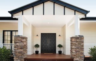 The front facade of a modern home with black double doors