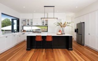 A modern black and white kitchen with rust-coloured bar stools.
