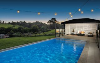 A pool area with lighting and countryside views at dusk