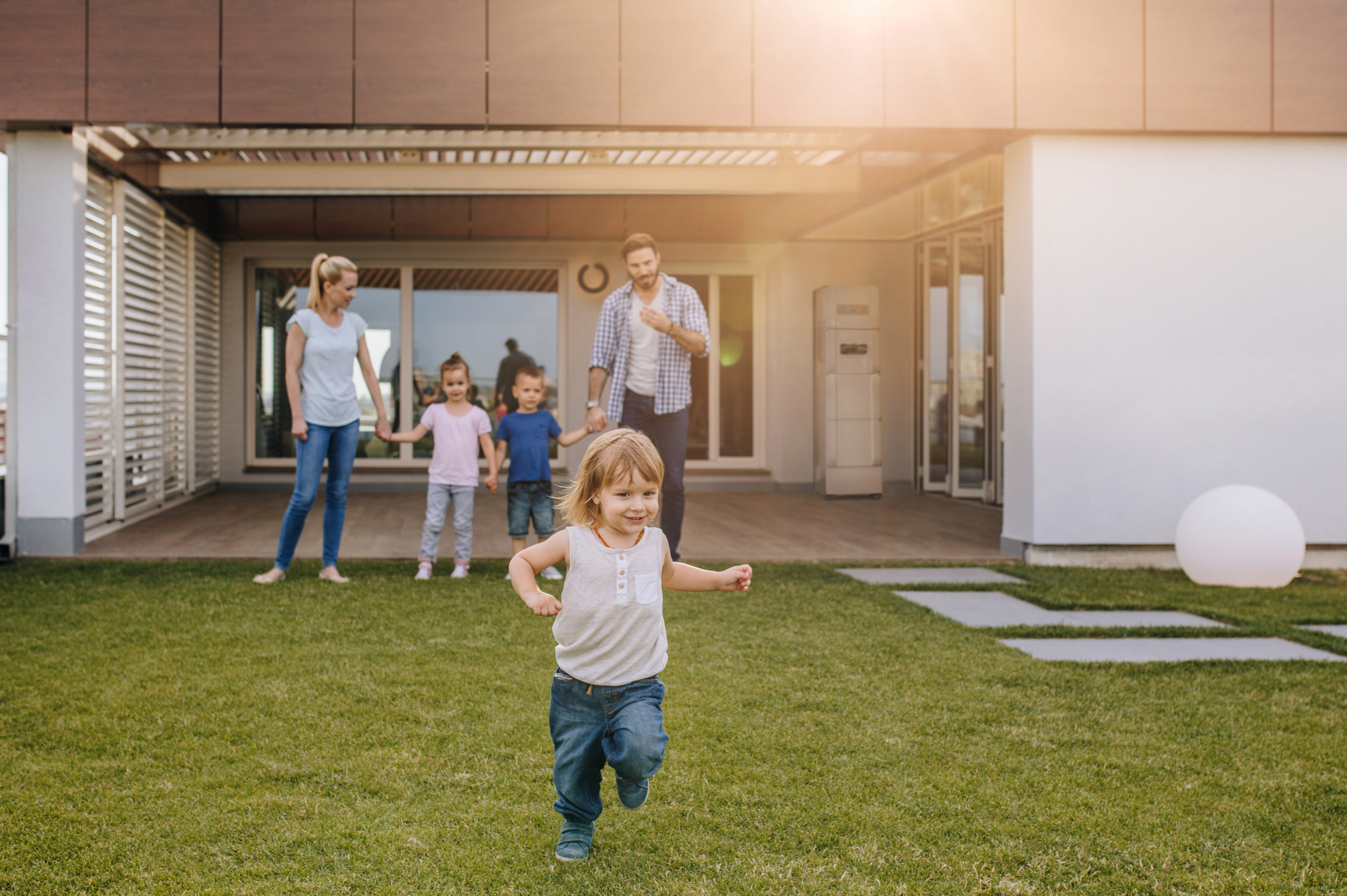 Happy little boy running and having fun with his family in the front of their house that has a Redback Technologies Smart Hybrid System installed.