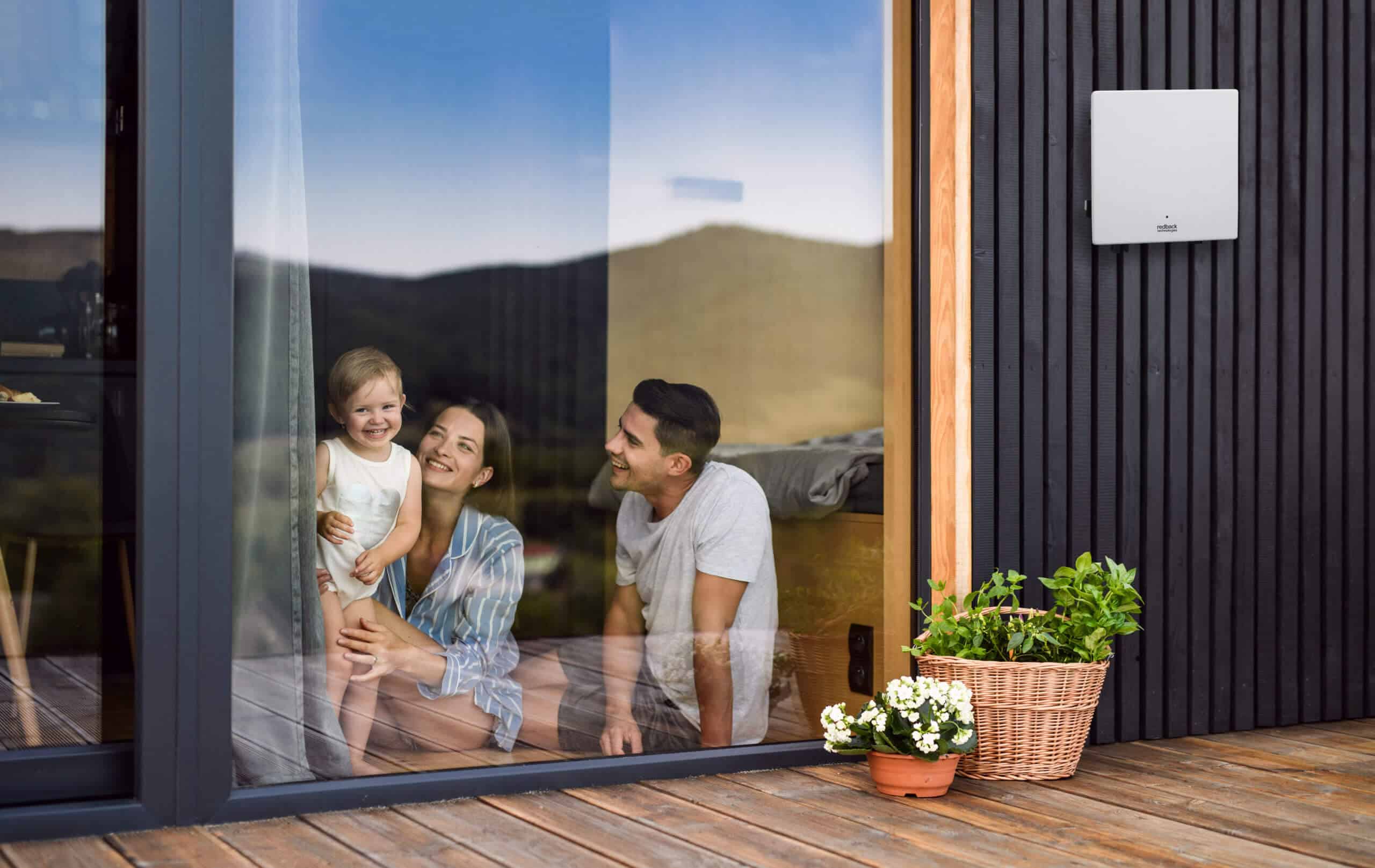 A family inside their home with a smart inverter on the wall outside.