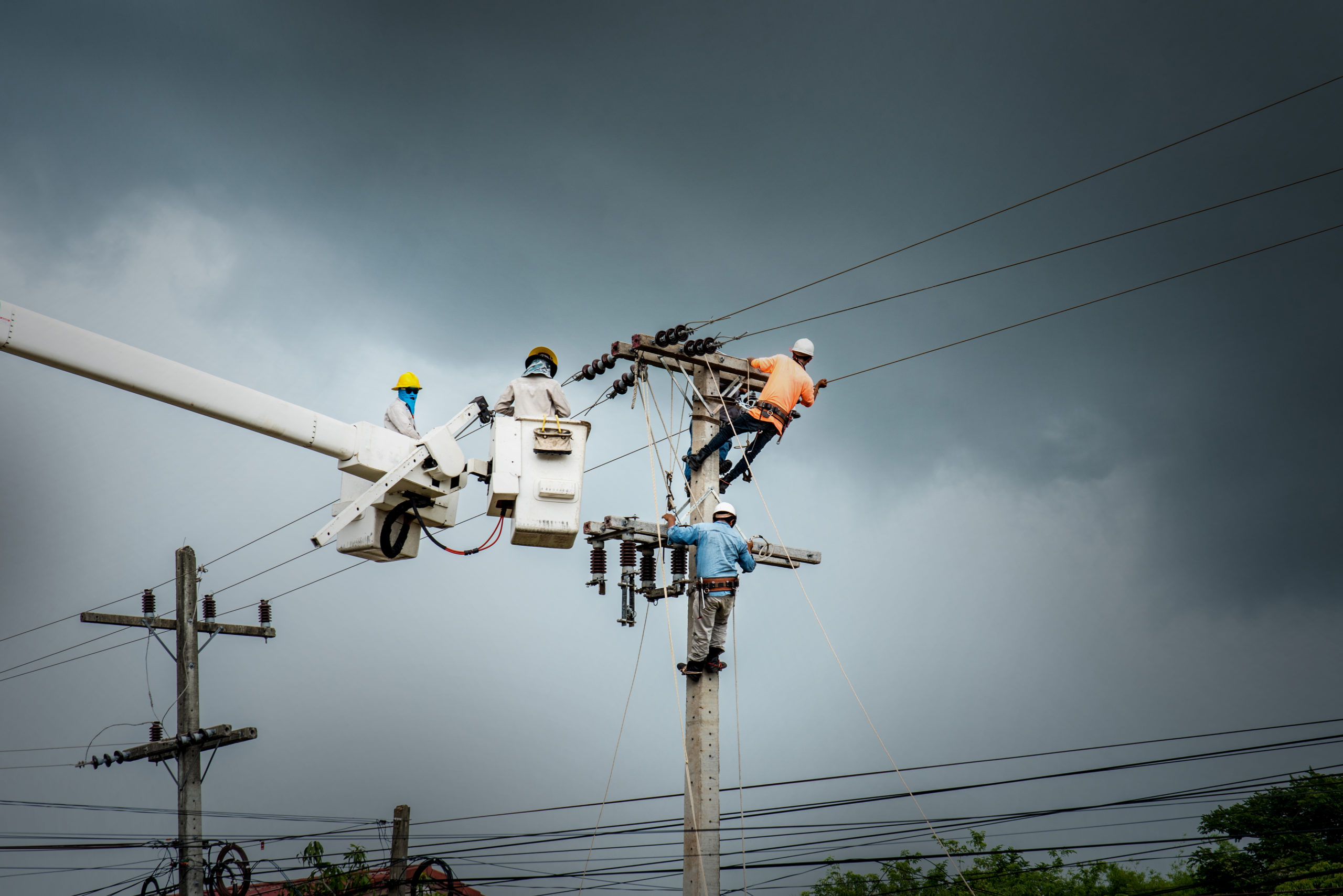 Electricians at work up power poles.