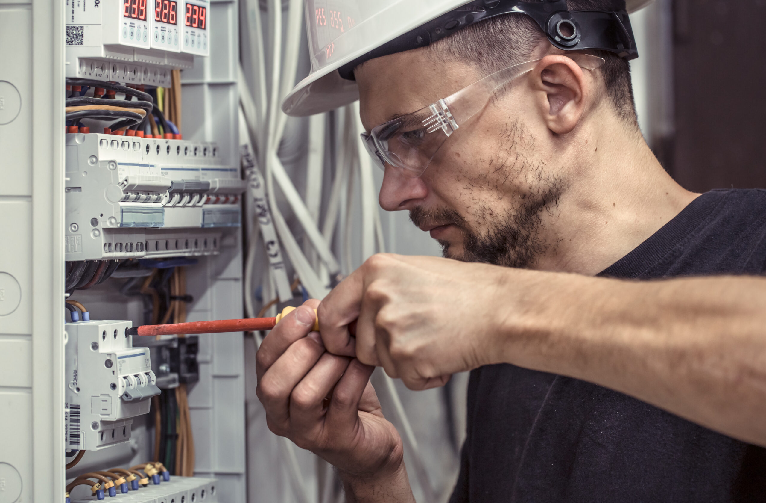 A male electrician works on a switchboard