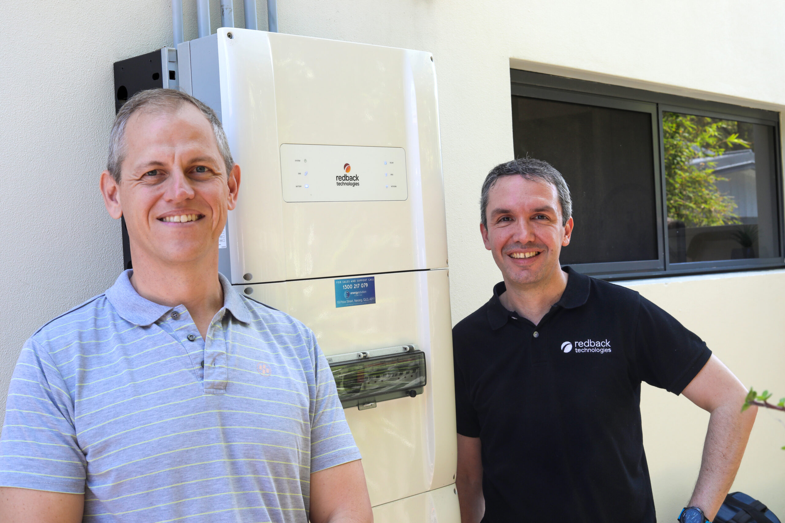 One of the Redback Technologies team with a Channel 10 News presenter standing by a Redback Technologies solar unit