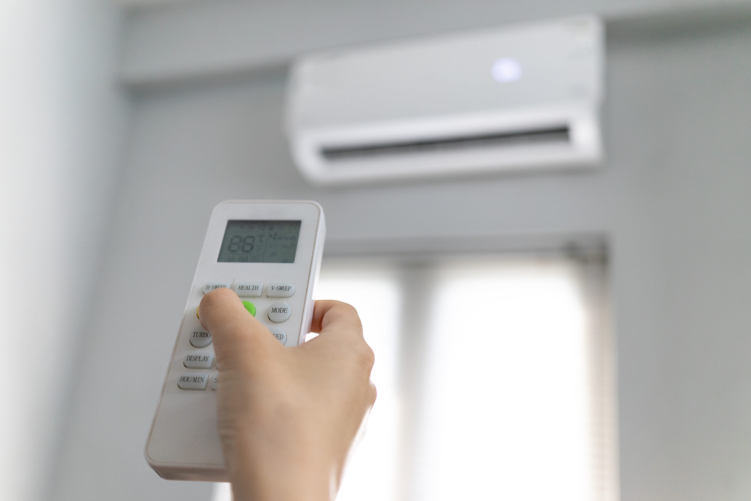Woman adjusts air conditioning temperature with control